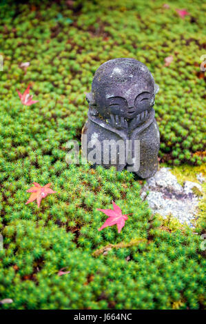 Statue en pierre de Jizo sur sol recouvert par green star moss et feuilles d'érable rouge au cours de l'automne dans un jardin à Enkoji temple de Kyoto, Japon Banque D'Images