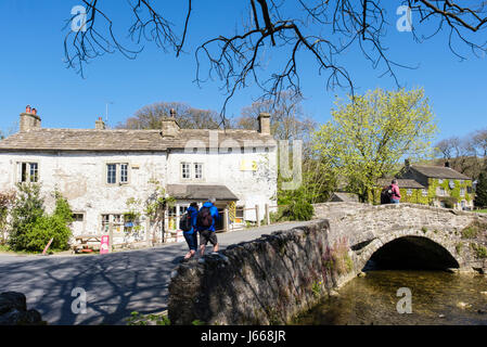Les randonneurs à pied sur le vieux pont au-dessus de Malham Beck. Malham, Malhamdale, Yorkshire Dales National Park, North Yorkshire, Angleterre, Royaume-Uni, Angleterre Banque D'Images