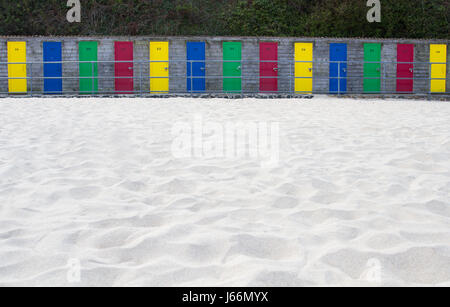 Une rangée de cabanes de plage avec des portes colorées, sur une plage de sable blanc avec copie espace ci-dessous. Banque D'Images