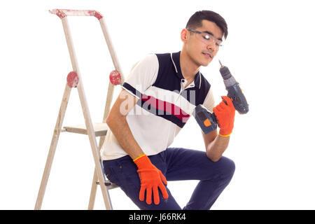 Young man holding tournevis électrique et assis sur ledder Banque D'Images