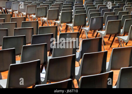 Des chaises en plastique gris disposés en rangées pour un concert ou une présentation dans un hall vide ou à l'auditorium Banque D'Images