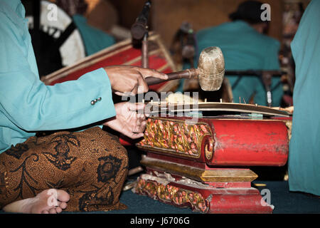 Le Gamelan instruments étant joué par un homme en Sarong batik javanais traditionnel au rendement. Photo d'un gamelan xylophone joué au concert Banque D'Images