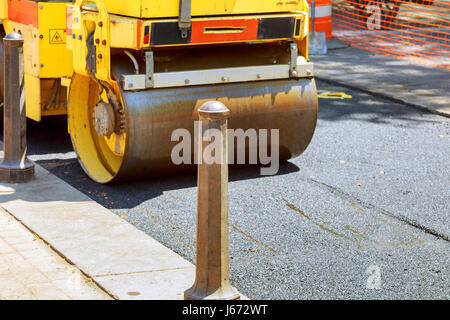 La route en milieu urbain est en cours de construction, de l'asphaltage en cours, fragment de rouleau jaune Banque D'Images