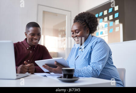 Deux jeunes collègues de bureau africain avec une tablette de travail Banque D'Images