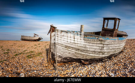 Vieux bateaux de pêche abandonnés sur une plage de galets avec une longue exposition des nuages. Dungeness, Angleterre Banque D'Images