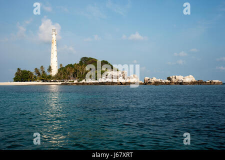 Phare de l'île blanche debout sur la plage avec des roches en Belitung dans la journée avec pas de gens autour. Banque D'Images