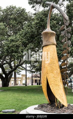 Napier, Nouvelle-Zélande - mars 9, 2017 : l'or de la statue de Paul Kowhai Plantoir à Beach park et Tennyson street intersection. Vert des arbres à l'arrière. Banque D'Images