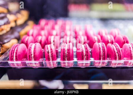 Gros plan macro de rangée de nombreux macarons roses à la vente en exposition à la boulangerie derrière le verre Banque D'Images