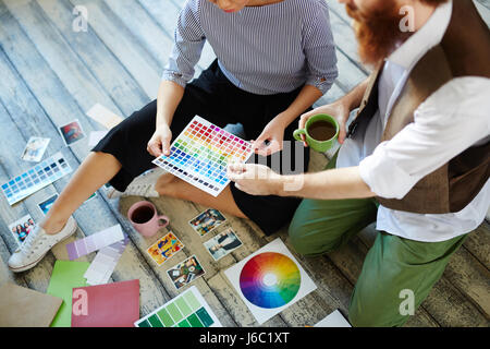 Équipe de concepteurs créatifs de discuter du projet, le choix d'échantillons de couleurs pose sur plancher en bois Banque D'Images