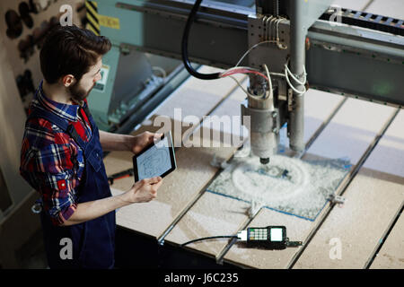 Machine de découpe d'exploitation des travailleurs de l'usine using digital tablet in workshop Banque D'Images