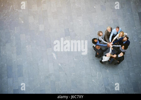 Au-dessus du noir et blanc joyeux office workers standing in hall avec mains empilés pdt teambuilding. Banque D'Images