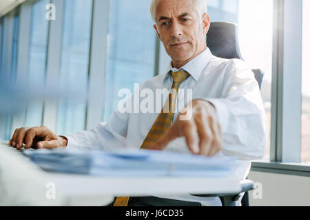 Shot of businessman assis à son bureau et de travail. Senior male entrepreneur dans son bureau. Banque D'Images