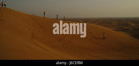 Ciel bleu du soir lumière du soleil paysage désert vue vers les touristes debout et se détendre sur la crête de dune de sable élevé, Alpha Tours Desrt Safari, Dubaï, Émirats arabes Unis Banque D'Images