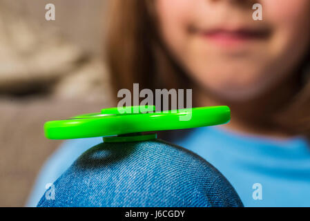 Little girl Playing with green fidget spinner toy pour soulager le stress à la maison Banque D'Images