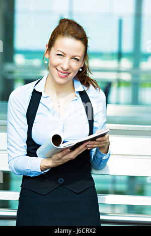 Closeup portrait femme d'affaires, la lecture de l'éditeur actu en magazine, smiling happy, great news article, des idées d'arrière-plan du bureau de l'entreprise isolée Banque D'Images