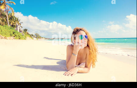 Happy young woman with sunglasses portant sur la plage. Banque D'Images
