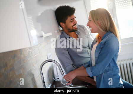 Jeune couple dans l'amour à faire la vaisselle dans la cuisine et souriant Banque D'Images