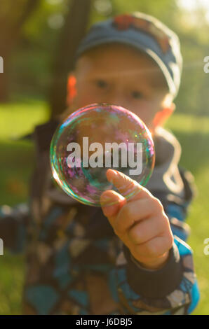 Le garçon tente d'attraper une bulle avec votre doigt.