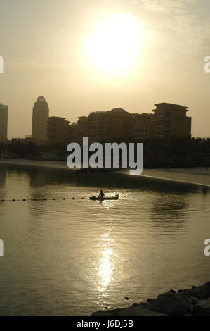 Portrait de l'homme par l'canoe natation réglage ligne net diviseur, Mina Seyahi Beach Resort, à lever de soleil au-dessus de Westin Hotel, Dubai, Émirats Arabes Unis Banque D'Images