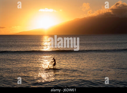 Un homme sur un paddle-board au coucher du soleil à Napili Bay, Maui, Hawaii. Banque D'Images