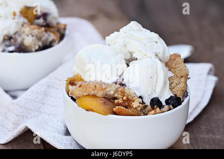 Fresh peach cobbler aux bleuets et servi avec de la glace à la vanille. Profondeur de champ avec focus sélectif. Banque D'Images