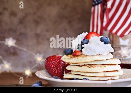 Pancakes servis avec des bleuets, fraises et crème fouettée contre un fond rustique. Parfait pour les quatrième de juillet. Profondeur de champ avec Banque D'Images