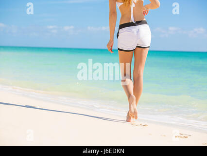 Plage voyager. Femme marche sur la plage de sable en laissant des traces de pas dans le sable. Closeup détail pieds femelles et de sable blanc sur la plage des Bahamas caraïbes destina Banque D'Images