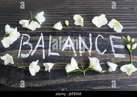 Mot équilibre avec fleurs de jasmin sur un fond de bois rustique. Banque D'Images