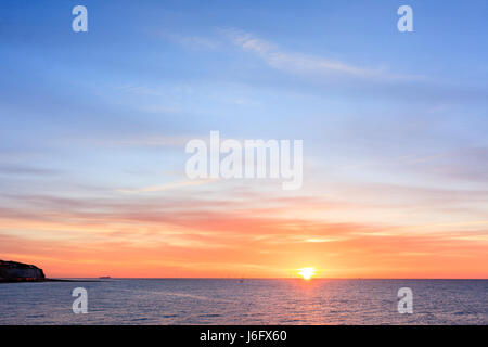 Lever de soleil sur la manche vu de Ramsgate, dans le Kent. Littoral sur bord du cadre. Jaune et orange du ciel le long de l'horizon bleu. Banque D'Images