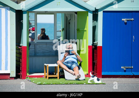 Brighton, UK. 21 mai, 2017. Le soleil à leurs cabanes de plage profiter du magnifique temps ensoleillé sur Hove front cet après-midi avec demain devrait être la journée la plus chaude de l'année Crédit : Simon Dack/Alamy Live News Banque D'Images