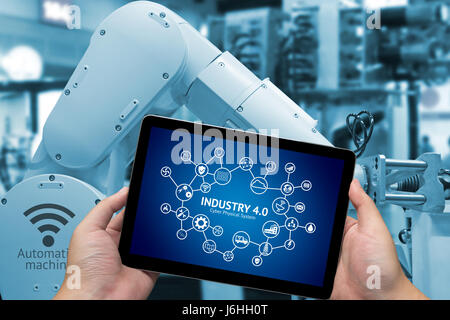 Internet des objets industriels .man main concept holding tablet avec l'Infographie Industry4.0 écran Icônes et ton bleu d'automatiser les bras de robot sans fil Banque D'Images