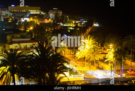 Vue de nuit brouillée avec des lumières colorées de la promenade et une aire de jeux dans un hôtel à Playa las Americas à Teneriffe dans les îles Canaries Banque D'Images