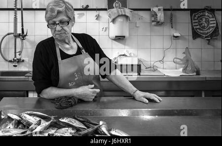 Poissonnier dans la boutique regardant le poisson sur un comptoir au Portugal Banque D'Images