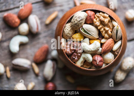 Noix mélangées séchées à bol en bois libre. Pistache, noix, noisette, amande et d'autres. L'analyse macro Studio. Banque D'Images