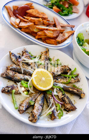 Des sardines grillées sur une plaque avec du citron et des pommes de terre sautées Banque D'Images