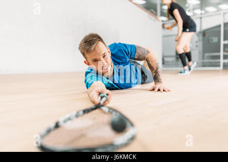 Formation de squash, football player avec racket se trouve sur le sol. Active sport d'entraînement. Jeu avec balle et raquette Banque D'Images