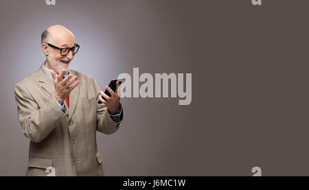 Portrait de funny senior man sur votre téléphone avec copie espace gris Banque D'Images