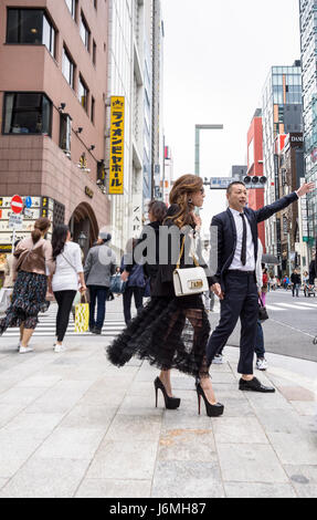 Jeune couple japonais dans le quartier branché de Ginza, Tokyo, hélant un taxi. Jeune couple moderne et soucieux de la mode. Banque D'Images