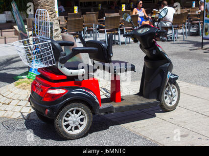 Une batterie powered scooter handicap engagé par un vacancier à Playa Las Americas à Teneriffe dans les îles Canaries Banque D'Images