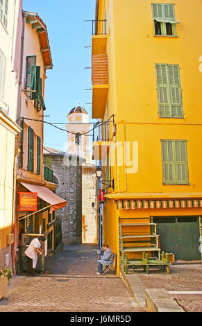 Villefranche-sur-Mer, France - 22 février 2012 : la rue étroite avec de petites boutiques et échoppes et la vue sur le clocher de l'église St michel sur Banque D'Images