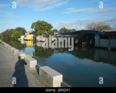 Une vue du paysage agricole à Sabang, Baliuag, Bulacan, Philippines, avec des rizières, prairies, maisons et systèmes d'irrigation reliés par des ponts routiers. Banque D'Images