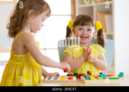 Les enfants Les enfants jouent avec des jouets éducatifs, l'organisation et le tri des couleurs et des formes. L'apprentissage par l'expérience de la conception. Banque D'Images