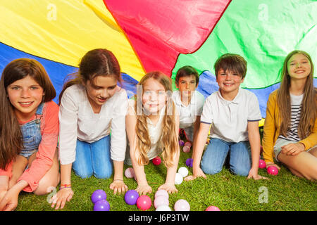 Portrait d'enfants heureux de se cacher sous l'auvent en parachute coloré extérieur en été Banque D'Images