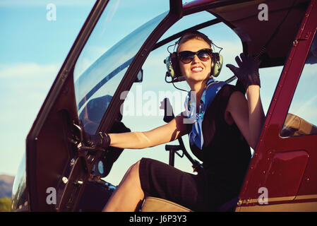 Jolie femme pilote assis dans l'hélicoptère Banque D'Images