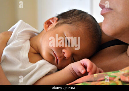 Dix jours bébé couché sur les genoux de sa mère après l'allaitement. Dormir sereinement dans l'après-midi. Banque D'Images