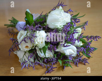 Un bouquet bouquet de roses blanches et arrangement violet mauve Statice Limoniun fixant sur le côté de la table Banque D'Images