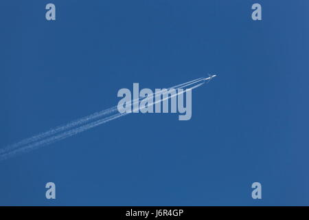 Un Boeing 747 laisse derrière elle vaportrails en volant dans un ciel bleu clair Banque D'Images