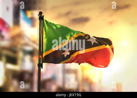 Saint Kitts-et-Nevis Flag contre ville fond flou de contre-jour au lever du soleil Banque D'Images