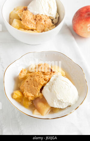 Peach cobbler fait maison avec de la glace à la vanille sur fond de bois rustique - dessert pâtisserie saine Banque D'Images