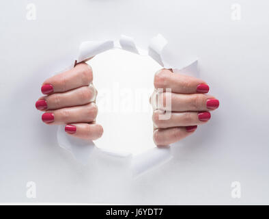 Woman's hands de déchirer le trou sur un papier. Banque D'Images